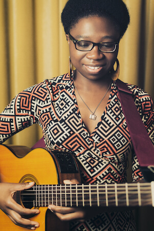 Photo of Djana Gabrielle holding a guitar and smiling